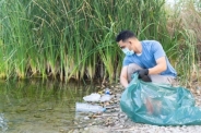Premium Photo | Close up of person collecting plastic from the river. man  cleaning river of plastics.